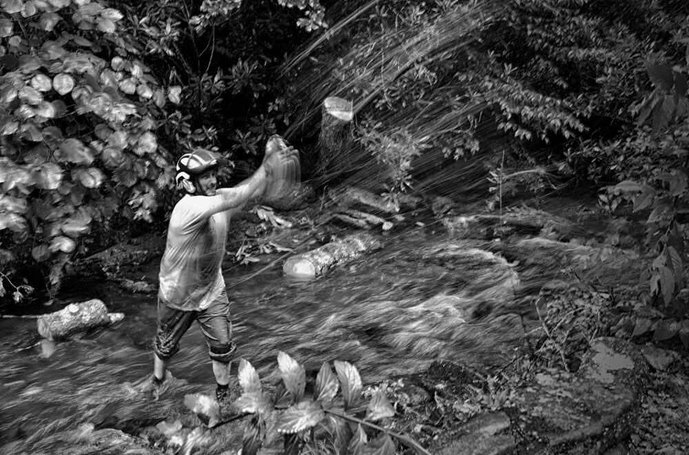 Jesse Latendresse working a tree removal job, throwing a log across a stream in the North Carolina High Country